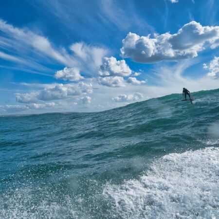 A foiler riding an Atlantic swell behind a jet ski at Vila Nova de Milfontes, Portugal