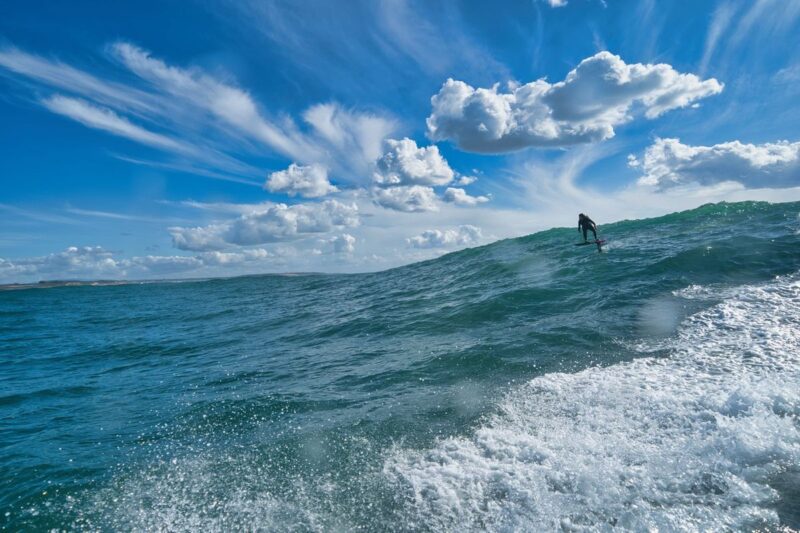 A foiler riding an Atlantic swell behind a jet ski at Vila Nova de Milfontes, Portugal